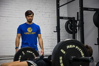 A man is standing next to a barbell in a gym.
