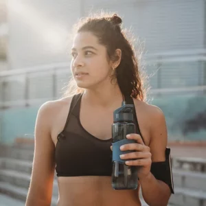 A woman in a sports bra holding a water bottle.