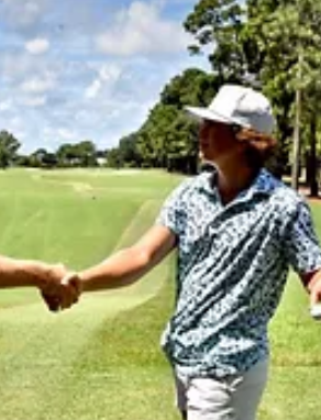 Two men shaking hands on a golf course.