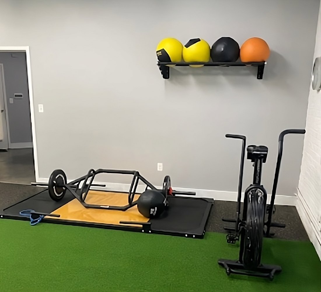 A gym room with exercise equipment and balls on the floor.