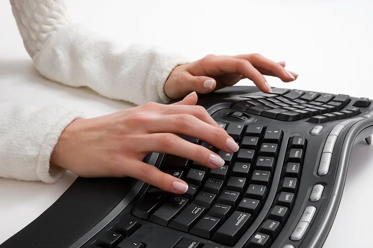 A woman's hands typing on a computer keyboard.