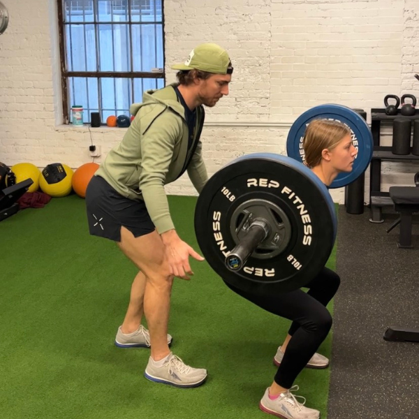 A man and woman doing squats in a gym.