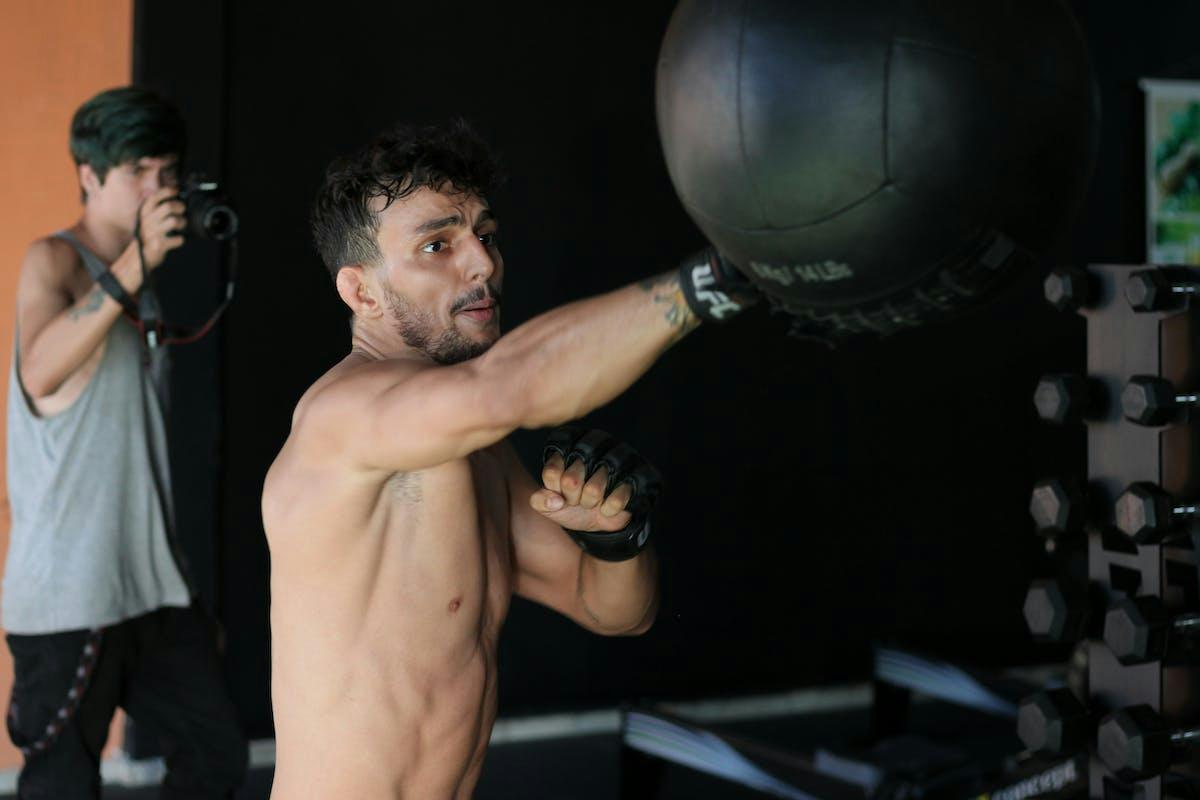 A man is punching a boxing ball in a gym.