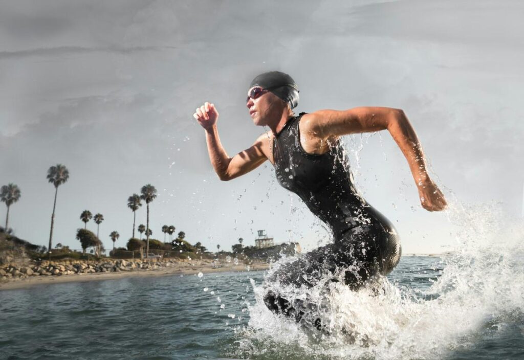 A woman in a wetsuit running in the ocean.